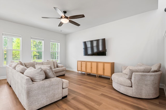 living area featuring light wood-type flooring, baseboards, and ceiling fan
