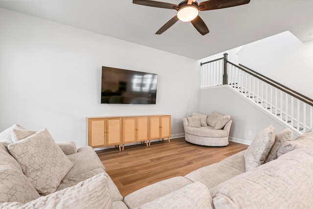 living area featuring wood finished floors, a ceiling fan, and baseboards