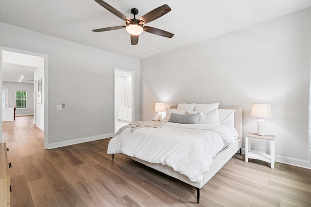 bedroom featuring wood finished floors, baseboards, a ceiling fan, and connected bathroom