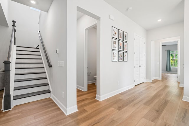 foyer featuring light wood-type flooring, baseboards, stairway, and recessed lighting