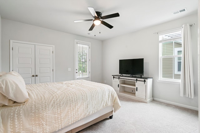 bedroom with light carpet, a closet, baseboards, and a ceiling fan