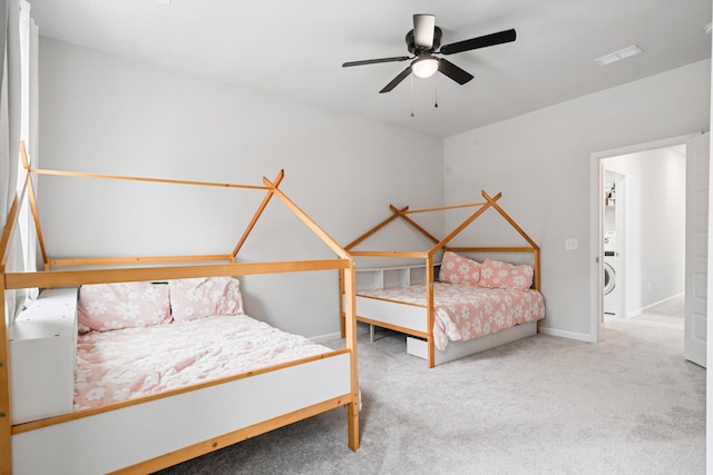 carpeted bedroom featuring stacked washer / dryer, baseboards, and a ceiling fan