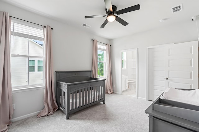 bedroom featuring light carpet, baseboards, a ceiling fan, and ensuite bathroom