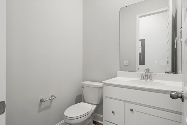 half bath with toilet, vanity, and baseboards