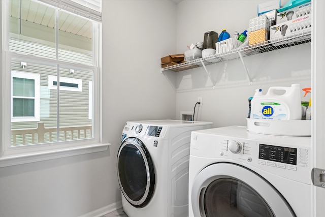 clothes washing area with washer and clothes dryer and baseboards