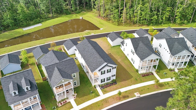 aerial view of residential area featuring a forest and a nearby body of water