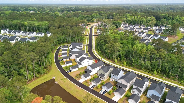 aerial view of property and surrounding area with a heavily wooded area, nearby suburban area, and a large body of water