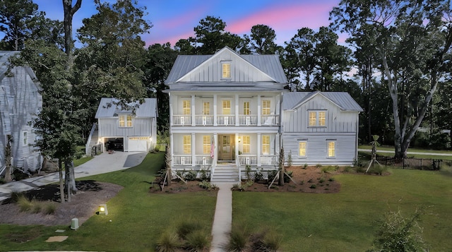 back of house at dusk featuring a porch, a lawn, board and batten siding, and a balcony