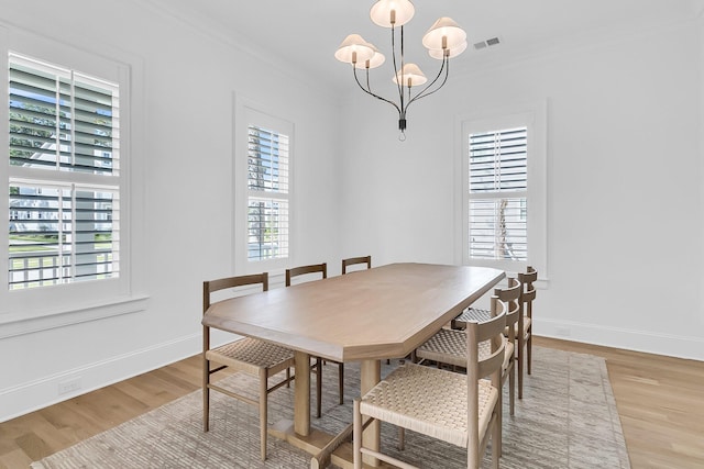 dining area featuring visible vents, light wood-style floors, ornamental molding, and a chandelier