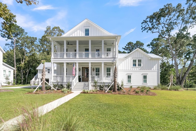 view of front of house with board and batten siding, a porch, a front yard, a balcony, and a ceiling fan