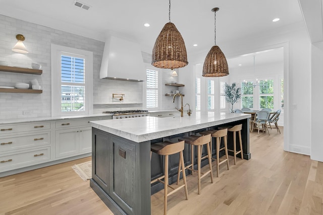 kitchen featuring open shelves, visible vents, light wood finished floors, and wall chimney range hood