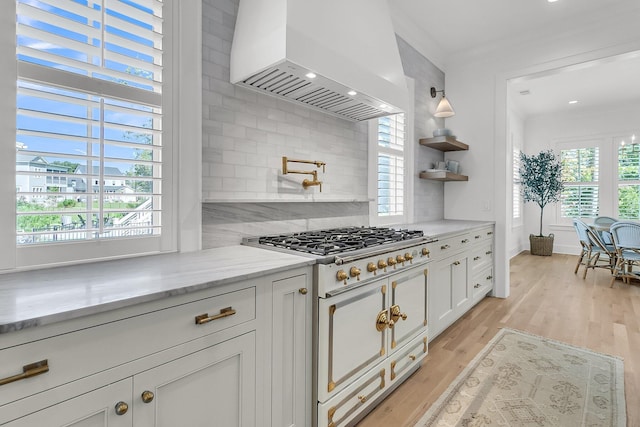 kitchen featuring ornamental molding, light wood-style flooring, double oven range, white cabinetry, and custom exhaust hood