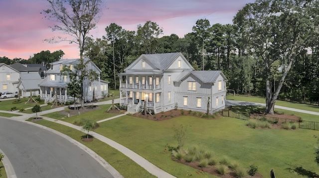 view of front of property featuring a front yard, fence, a porch, board and batten siding, and metal roof