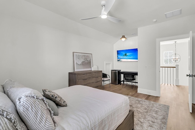 bedroom featuring visible vents, baseboards, light wood-style flooring, vaulted ceiling, and ceiling fan with notable chandelier