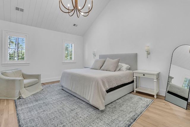 bedroom with wood finished floors, visible vents, a chandelier, and baseboards