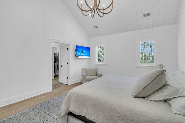 bedroom featuring a spacious closet, wood finished floors, visible vents, and baseboards