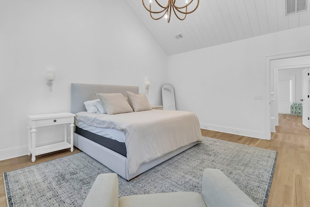 bedroom with visible vents, wood finished floors, baseboards, and vaulted ceiling