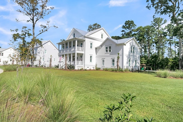 back of house featuring a lawn, board and batten siding, and a balcony