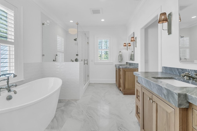 full bath with visible vents, two vanities, a sink, a shower stall, and a freestanding bath