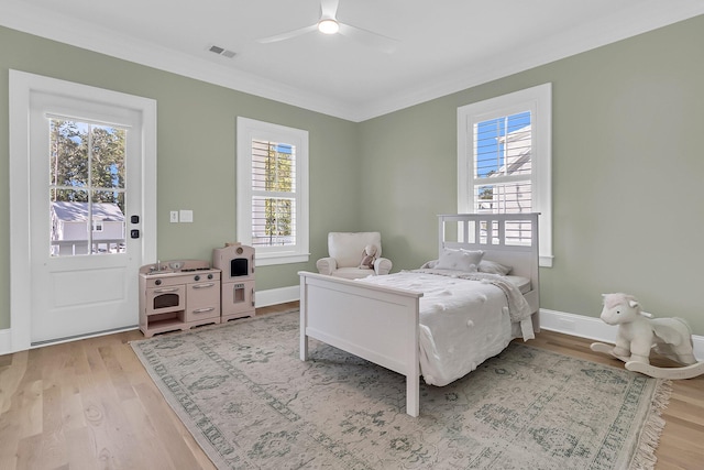 bedroom with visible vents, baseboards, crown molding, and light wood-style floors