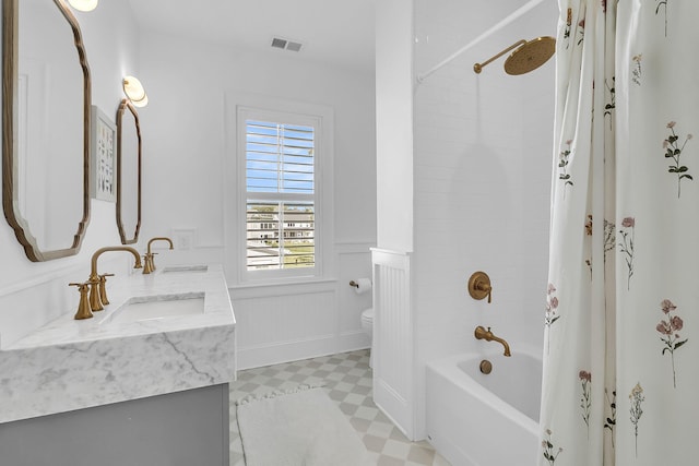 bathroom featuring visible vents, wainscoting, toilet, and a sink