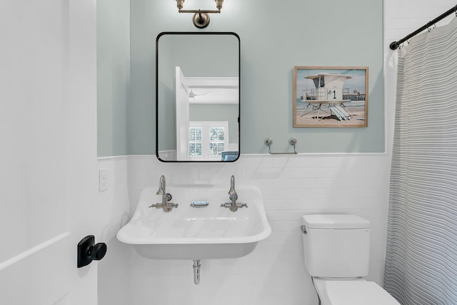 full bath featuring a sink, a wainscoted wall, toilet, and tile walls