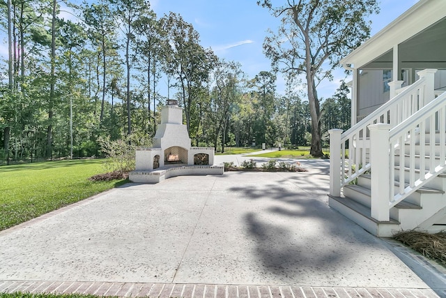 view of patio / terrace featuring stairs, driveway, and a lit fireplace