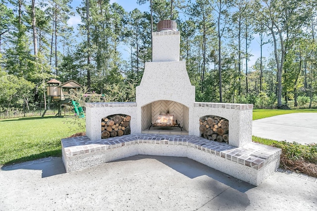 view of patio featuring a playground and an outdoor brick fireplace