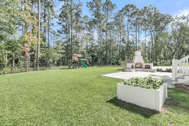 view of yard with exterior fireplace, a playground, and fence