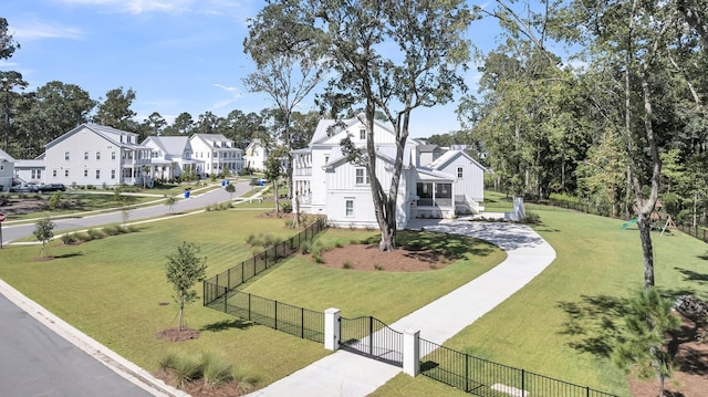 view of community with a gate, a yard, a residential view, and fence