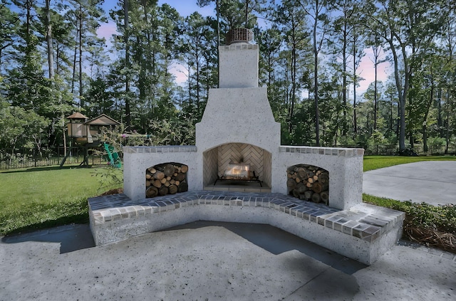 view of patio with a playground and an outdoor brick fireplace