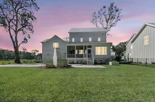 rear view of house with fence, a lawn, metal roof, a sunroom, and crawl space