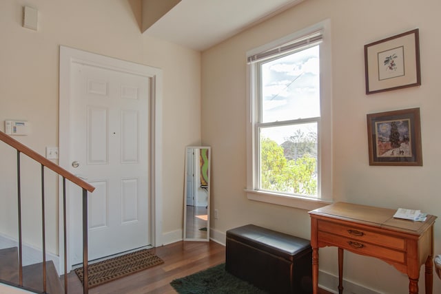 foyer entrance with stairs, baseboards, and wood finished floors