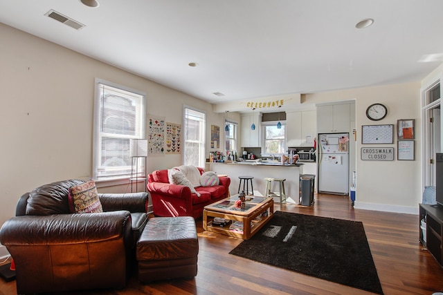 living area featuring visible vents, baseboards, and dark wood-style flooring