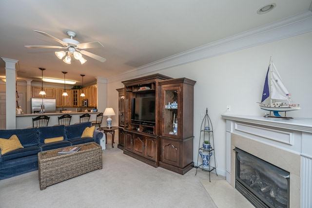living room with light colored carpet, ornamental molding, a ceiling fan, and a high end fireplace