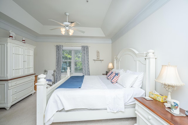bedroom featuring light colored carpet, a ceiling fan, ornamental molding, and a tray ceiling