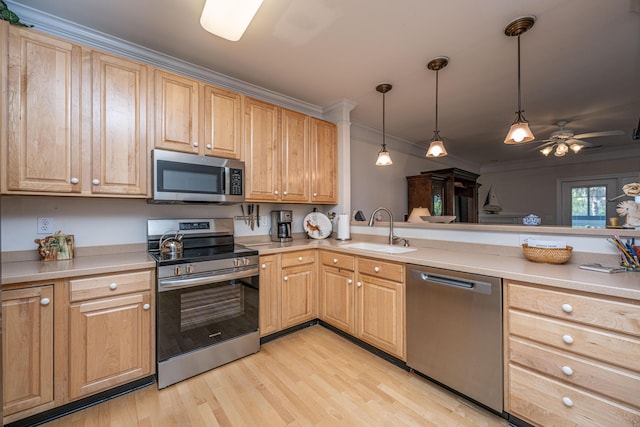 kitchen featuring stainless steel appliances, ornamental molding, a sink, light wood-style flooring, and hanging light fixtures