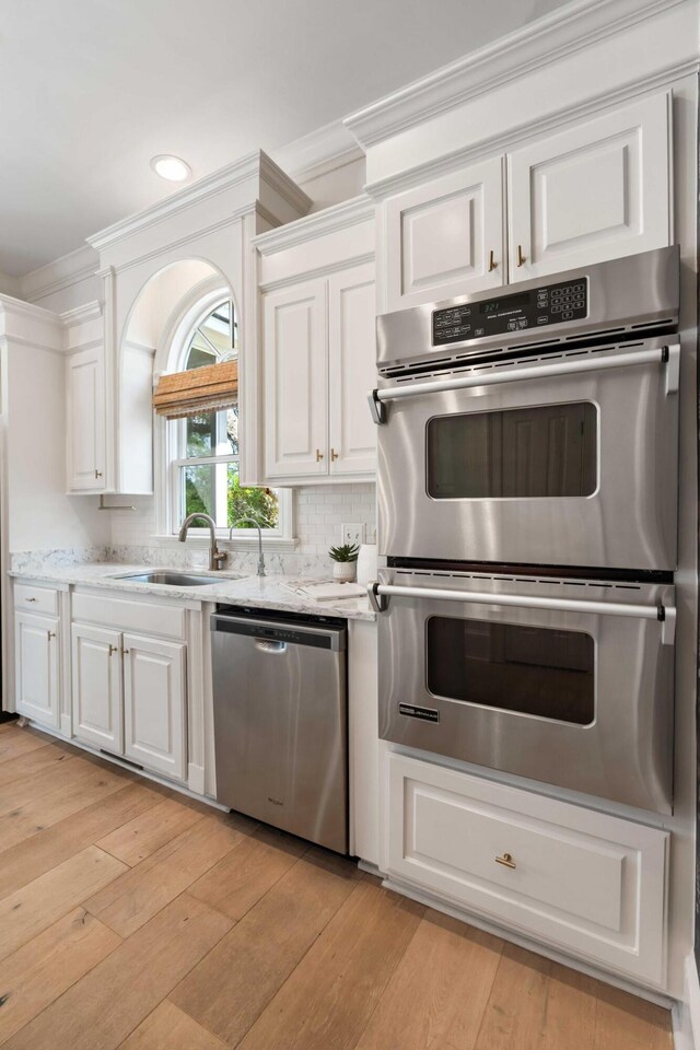 3508 Henrietta Hartford Rd, Mount Pleasant, SC 29466 - kitchen featuring stainless steel appliances, ornamental molding, a sink, white cabinetry, and light wood-style floors