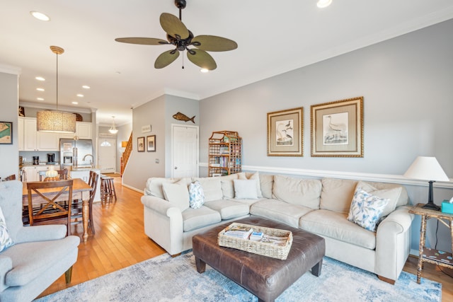 living room featuring light hardwood / wood-style flooring, ceiling fan, and crown molding