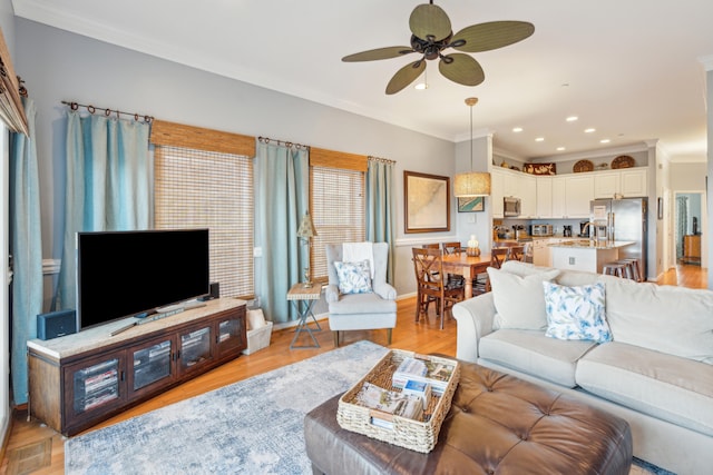 living room featuring ceiling fan, light hardwood / wood-style floors, and ornamental molding