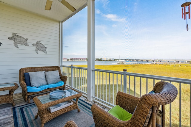 sunroom featuring ceiling fan and a water view