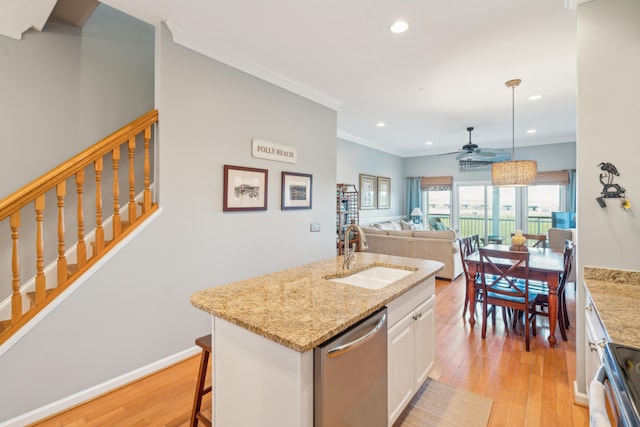 kitchen with sink, stainless steel appliances, light hardwood / wood-style flooring, a center island with sink, and white cabinets