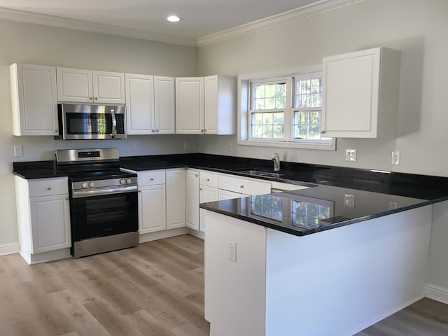 kitchen featuring sink, kitchen peninsula, white cabinetry, light hardwood / wood-style floors, and stainless steel appliances