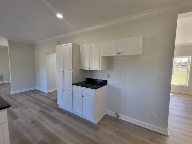 kitchen with light hardwood / wood-style floors, white cabinetry, and ornamental molding