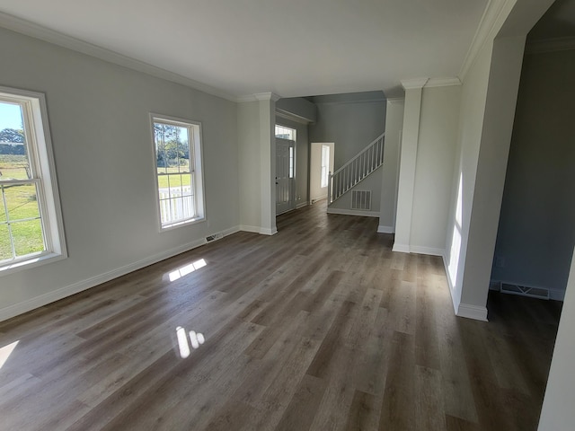 unfurnished living room featuring ornate columns, crown molding, a wealth of natural light, and dark hardwood / wood-style floors