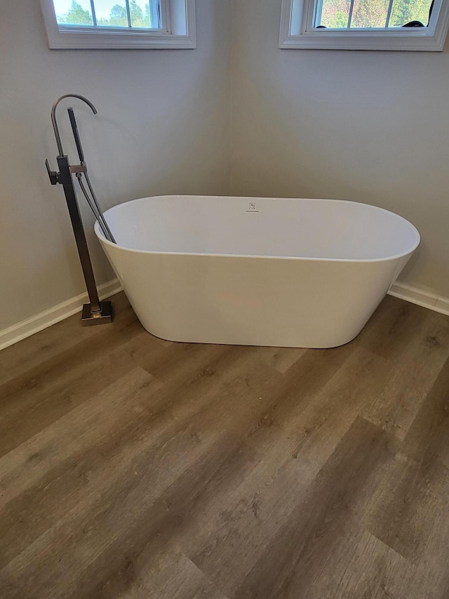 bathroom featuring a bathtub, hardwood / wood-style flooring, and a healthy amount of sunlight