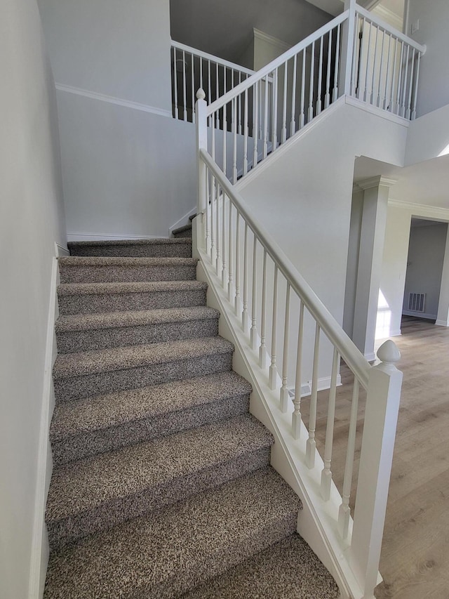 stairway with wood-type flooring and a high ceiling