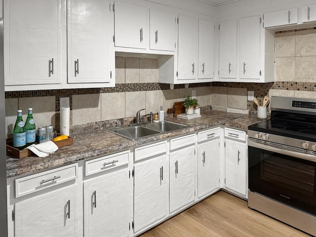 kitchen with sink, white cabinetry, electric range, light hardwood / wood-style floors, and decorative backsplash