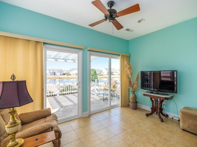 living area featuring light tile patterned floors, visible vents, ceiling fan, and baseboards