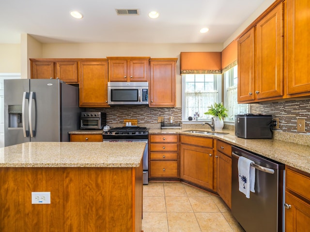 kitchen with visible vents, brown cabinets, a sink, appliances with stainless steel finishes, and light tile patterned floors